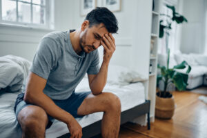 Worried man with his head in his hand considering his poor male body image due to infertility | Dallas IVF
