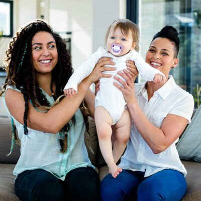 Lesbian couple holding baby after utilizing LGBTQ fertility services | Dallas IVF | Frisco TX