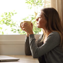 Woman holding coffee cup thinking about symptoms of PCOS | Dallas IVF | Frisco & Dallas, TX
